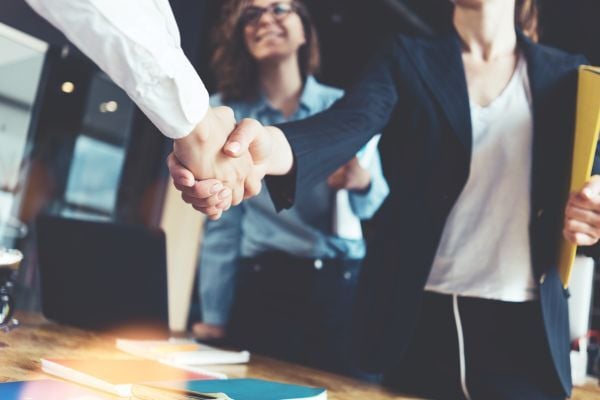 Two business women shaking hands, signifying a business deal Two business women shaking hands, signifying a business deal