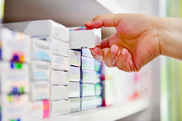 Hand pulling box of medication out from shelf