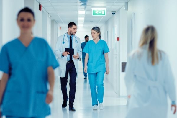 Two doctors walking in busy hospital hallway