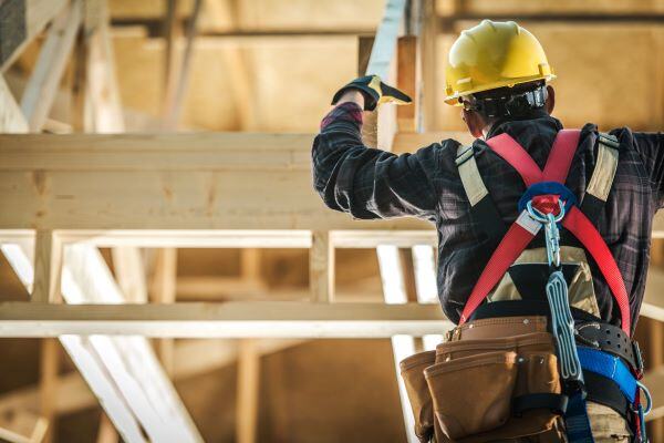 Construction worker in a harness working on wooden structure